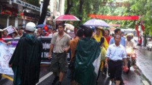 Người biểu tình đi trong mưa ở Hà Nội ngày 1/7/2012